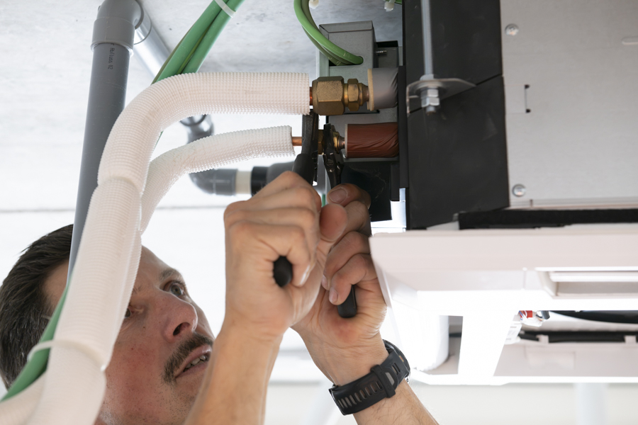 Fabrice sluit de leidingen aan op de airco unit in Zelzate.